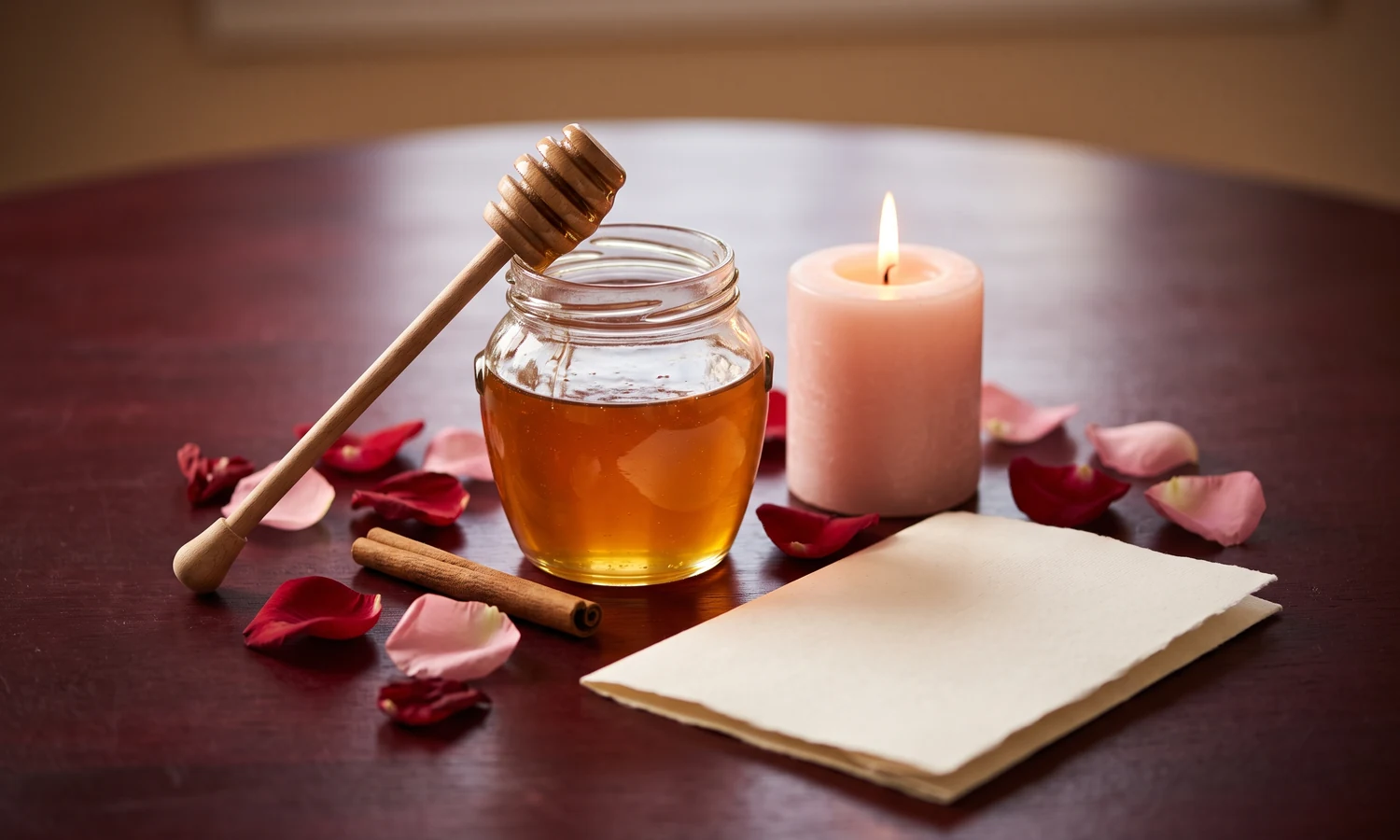 Honey jar, pink candle, rose petals and cinnamon stick