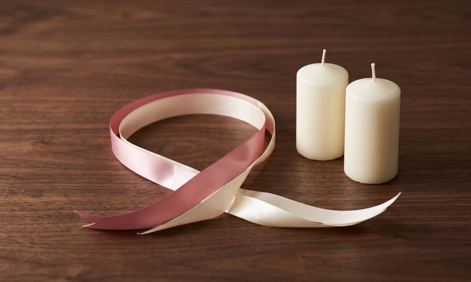 Pink and white ribbons with two candles symbolizing consensual love binding